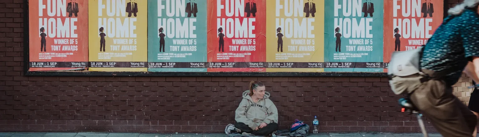 woman sitting against a wall with posters all over the wall