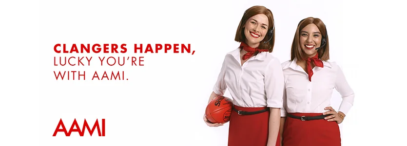 two women posing a smiling with an AFL football for an AAMI poster