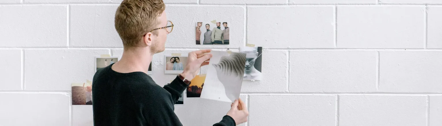 man putting pictures on a wall