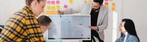 man presenting plans on a computer screen with others watching