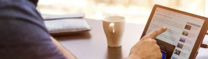 man on linkedin scrolling down on his tablet with a coffee mug